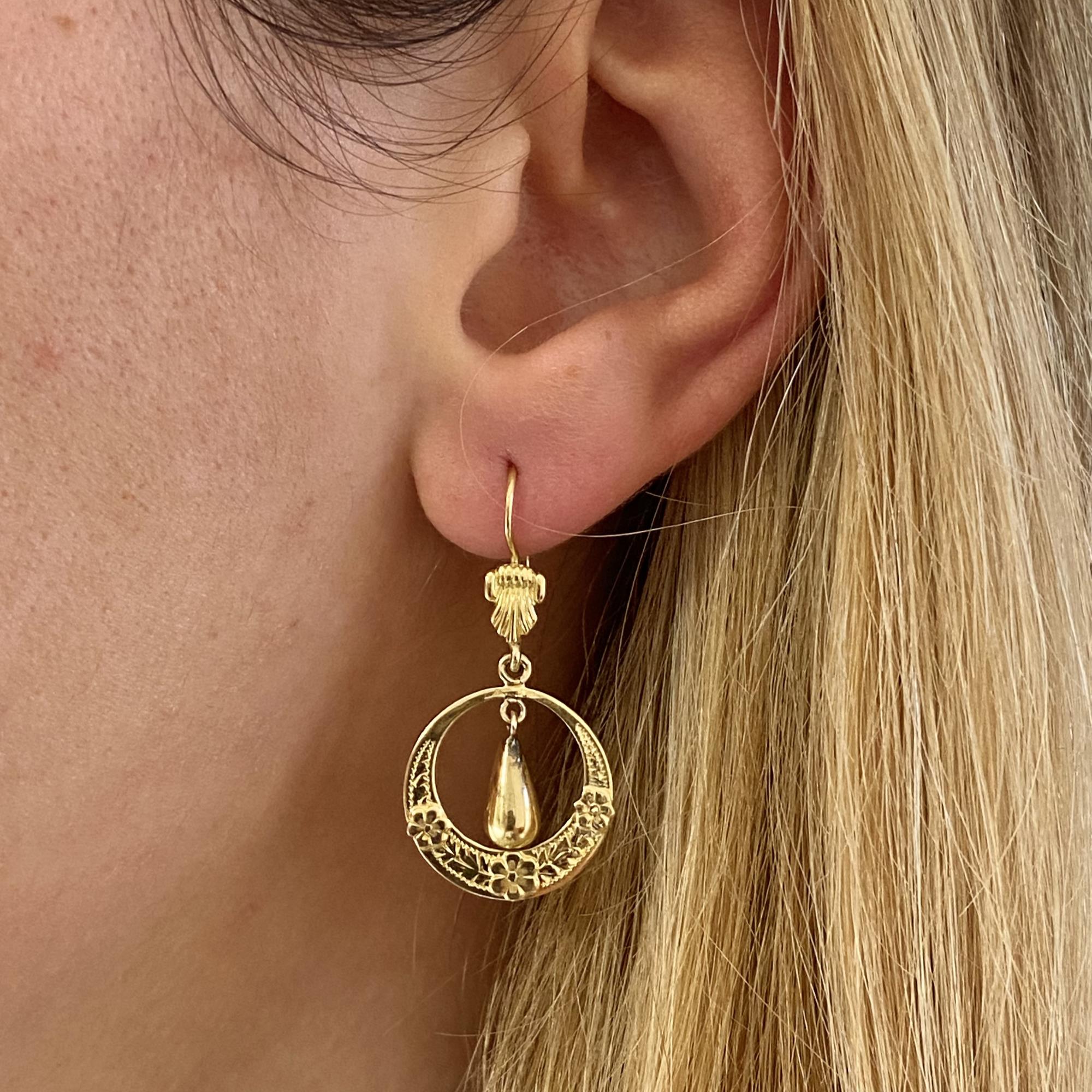 Dangling earrings in 18kt gold with delicate floral decorations.